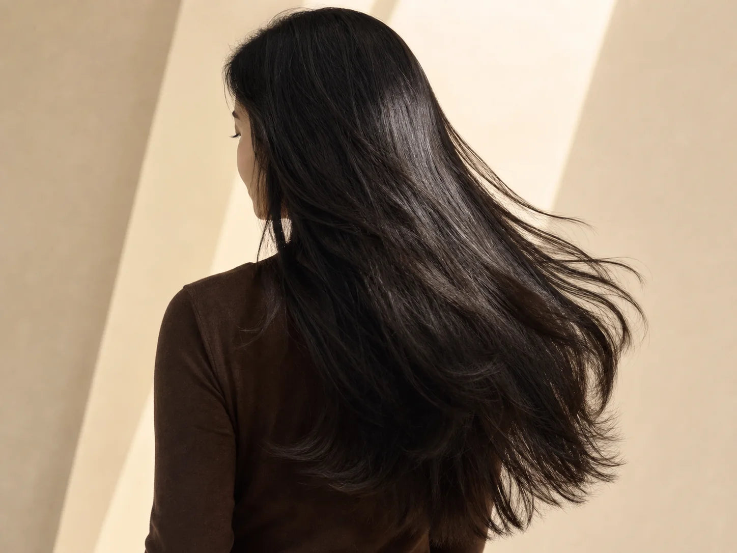 Smooth natural-black hair moving softly in warm light